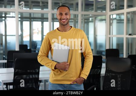 Schöner glücklicher Mann mit Laptop im Büro Stockfoto