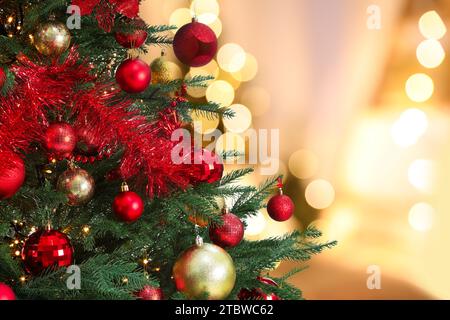 Weihnachtsbaum mit roten und goldenen Weihnachtskugeln vor verschwommenem Hintergrund, Bokeh-Effekt. Leerzeichen für Text Stockfoto