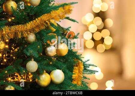 Weihnachtsbaum mit goldenen Weihnachtskugeln vor verschwommenem Hintergrund, Bokeh-Effekt. Leerzeichen für Text Stockfoto
