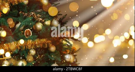 Weihnachtsbaum mit goldenen Weihnachtskugeln vor verschwommenem Hintergrund, Bokeh-Effekt. Bannerdesign mit Platz für Text Stockfoto