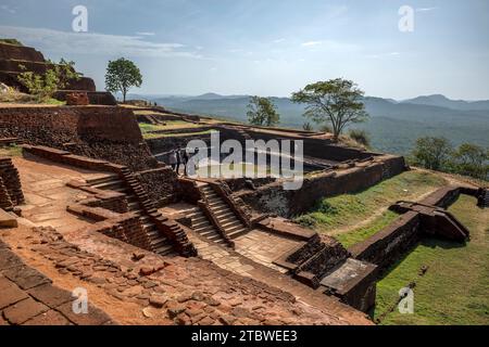 Die verschiedenen roten Backsteinmauern und Treppen, die den künstlichen Wassertank umgeben, der aus massivem Felsen auf dem Gipfel des Sigiriya Rock i Sri Lanka gemeißelt wurde Stockfoto