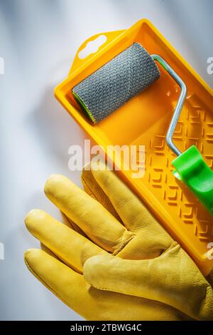 Gelbe Schutzhandschuhe Malerwalze auf weißer Oberfläche Stockfoto