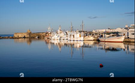 Fischerboote im Hafen und Ruinen der venezianischen Burg, reflektiert im Meer, bei Sonnenuntergang, Naoussa, Paros, Kykladen, Griechenland Stockfoto