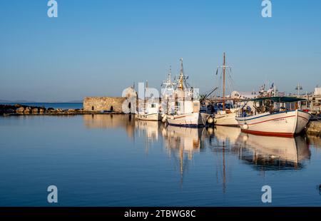 Fischerboote im Hafen und Ruinen der venezianischen Burg, reflektiert im Meer, bei Sonnenuntergang, Naoussa, Paros, Kykladen, Griechenland Stockfoto