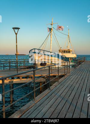 Ein Bild eines Fischerbootes, das bei Sonnenuntergang neben einem Pier in Limassol ruht Stockfoto