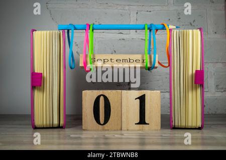 Bunte September noch leben mit Büchern, Gummibänder und rustikalen Zeichen für den Monat gegen eine weiße Wand Stockfoto