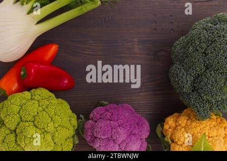 Rustikale Grenze von gesundem frischem Gemüse über Holz mit Copyspace einschließlich bunten Sorten von Blumenkohl, Brokkoli und roten Paprika, von denen aus gesehen wird Stockfoto