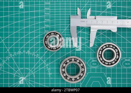 Gruppe von Rollenlagern und Bremssattel auf grüner Schneidmatte mit freiem Kopieplatz. Maschinenbau und Automobilindustrie Stockfoto