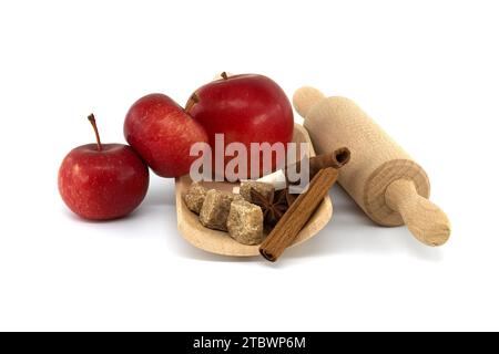 Zimtstangen, braune Zuckerwürfel und Anissterne in Holzlöffel neben roten Äpfeln Stockfoto