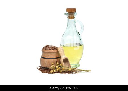 Leinsamenöl in Glasdekanter und Leinsamen in Holzschaufel in der Nähe von Flachsbäumen, isoliert auf weißem Hintergrund. Linum usitatissimum (Gemeiner Flachs) Stockfoto