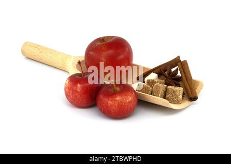 Rote Äpfel in der Nähe von Zucker, Zimtstangen und Anissterne in Holzlöffel gelegt. Backen Apfelkuchen Konzept isoliert auf weiß Stockfoto