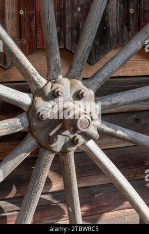 Ein altes hölzernes Wagenrad, das an der Wand einer Scheune hängt Stockfoto