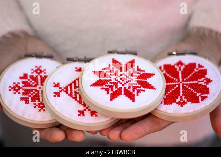 Frau mit handgemachtem Kreuzstich Folk Weihnachtsdekoration Stickerei auf Sperrholz. Nordische Schneeflocken Stockfoto