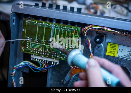Schwerin, Deutschland. November 2023. In einer kleinen Werkstatt für alte Radios, Plattenspieler und hifi-Anlagen werden elektronische Bauteile auf eine Leiterplatte einer in der DDR hergestellten hifi-Anlage verlötet. Elektrokleingeräte aus Ost und West sind hier seit rund 34 Jahren funktionsfähig. Stammkunden, die vor allem für die DDR-Funktechnik eine Schwäche haben, geben ihre Geräte an den ausgebildeten Radio- und Fernsehtechniker zurück. Mangelnde Ersatzteile und sinkendes Interesse bei jüngeren Kunden bedeuten, dass die Tage dieses einzigartigen Workshops dpa/Alamy Live News Stockfoto