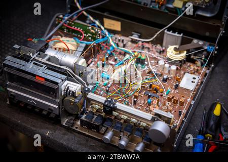 Schwerin, Deutschland. November 2023. In einer kleinen Werkstatt für alte Radios, Plattenspieler und hifi-Anlagen wird eine Leiterplatte mit elektronischen Bauteilen in einer Musikanlage der DDR-Firma RFT repariert. Elektrokleingeräte aus Ost und West sind hier seit rund 34 Jahren funktionsfähig. Stammkunden, die insbesondere für die DDR-Funktechnik sensibel sind, geben ihre Geräte an den ausgebildeten Radio- und Fernsehtechniker weiter. Mangelnde Ersatzteile und sinkendes Interesse bei jüngeren Kunden bedeuten, dass die Tage dieses einzigartigen Werkes dpa/Alamy Live News Stockfoto