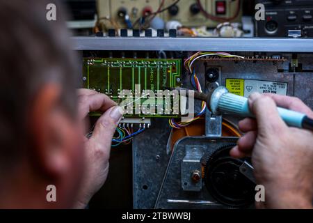 Schwerin, Deutschland. November 2023. In einer kleinen Werkstatt für alte Radios, Plattenspieler und hifi-Anlagen werden elektronische Bauteile auf eine Leiterplatte einer in der DDR hergestellten hifi-Anlage verlötet. Elektrokleingeräte aus Ost und West sind hier seit rund 34 Jahren funktionsfähig. Stammkunden, die vor allem für die DDR-Funktechnik eine Schwäche haben, geben ihre Geräte an den ausgebildeten Radio- und Fernsehtechniker zurück. Mangelnde Ersatzteile und sinkendes Interesse bei jüngeren Kunden bedeuten, dass die Tage dieses einzigartigen Workshops dpa/Alamy Live News Stockfoto