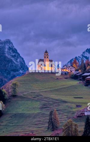 Die Kirche Chiesa Santa Lucia in Colle Santa Lucia am Fuße des Giau-Passes, Passo di Giau, beleuchtet in der Nacht im Herbst. Stockfoto