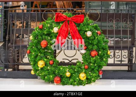 Weihnachtskranz aus Fichte mit roter Schleife und Glaskugeln am Zaun Stockfoto