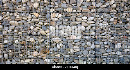 Steine texturierter Zaun Gabionstahl Metall Gitterstein Wandkorb aus Mesh und Steinen Hintergrund Stein und Kies in Metallkäfig eingeschlossen zu schaffen Stockfoto