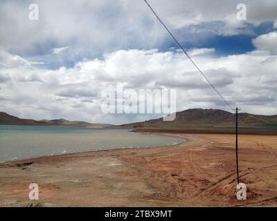 Eine ruhige und ruhige Landschaft mit einem trockenen Wüstengelände, mit einem entfernten Gewässer und dramatischen Bergketten im Hintergrund Stockfoto