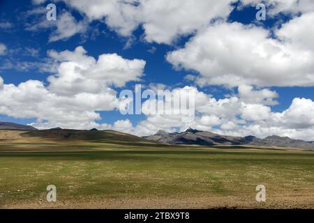 Ein majestätischer Blick auf sanfte Hügel, umgeben von einem weiten Himmel voller flauschiger weißer Wolken Stockfoto