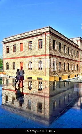 Junges Paar, das vor einem neoklassizistischen Gebäude läuft, das sich auf dem Platz widerspiegelt Stockfoto