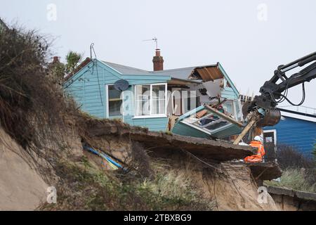 Abbrucharbeiter reißen das erste von fünf Häusern auf den Klippen des Dorfes Hemsby ab, das von der Küstenerosion betroffen ist. Hohe Fluten und starke Winde führten letzten Monat zum Zusammenbruch einer privaten Zufahrtsstraße in Hemsby in Norfolk. Bilddatum: Samstag, 9. Dezember 2023. Stockfoto