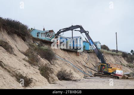 Abbrucharbeiter reißen das erste von fünf Häusern auf den Klippen des Dorfes Hemsby ab, das von der Küstenerosion betroffen ist. Hohe Fluten und starke Winde führten letzten Monat zum Zusammenbruch einer privaten Zufahrtsstraße in Hemsby in Norfolk. Bilddatum: Samstag, 9. Dezember 2023. Stockfoto