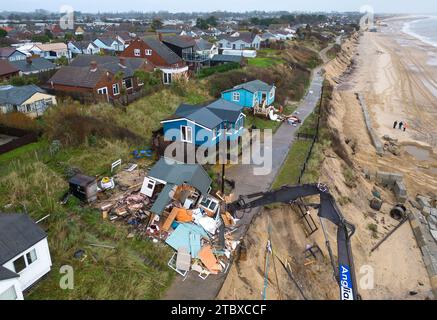 Abbrucharbeiter reißen das erste von fünf Häusern auf den Klippen des Dorfes Hemsby ab, das von der Küstenerosion betroffen ist. Hohe Fluten und starke Winde führten letzten Monat zum Zusammenbruch einer privaten Zufahrtsstraße in Hemsby in Norfolk. Bilddatum: Samstag, 9. Dezember 2023. Stockfoto