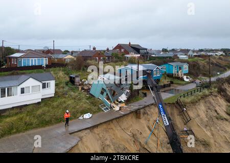 Abbrucharbeiter reißen das erste von fünf Häusern auf den Klippen des Dorfes Hemsby ab, das von der Küstenerosion betroffen ist. Hohe Fluten und starke Winde führten letzten Monat zum Zusammenbruch einer privaten Zufahrtsstraße in Hemsby in Norfolk. Bilddatum: Samstag, 9. Dezember 2023. Stockfoto