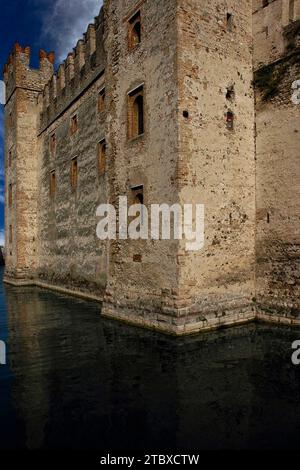 Abendsonnenlicht strahlt über die Außenwände des Castello Scaligero oder der Rocca Scaligera in Sirmione am Gardasee in der Lombardei, Italien. Die Burg wurde in den 1300er Jahren erbaut und hat ihren Namen von der Familie Della Scala, der Herrscherin in Verona, die das Gebiet zu dieser Zeit dominierte. Es ist eine der am besten erhaltenen Scaliger-Festungen. Die Burg verfügt über Schwalbenschwanzzinnen und Pfeilschlitze, die für mittelalterliche Bogenschützen entworfen wurden. Stockfoto