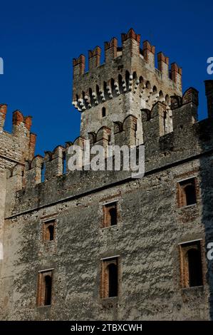 Ein 29 Meter hoher Turm erhebt sich über dem Castello Scaligero oder der Rocca Scaligera in Sirmione am Gardasee in der Lombardei, Italien. Es verfügt über Schwalbenschwanzmauern, die für mittelalterliche Bogenschützen ausgelegt sind, und Machicolations oder „Mordlöcher“, um Angreifer mit heißem Öl oder Felsbrocken abzuwerfen. Die Burg wurde in den 1300er Jahren erbaut und hat ihren Namen von der Familie Della Scala, der Herrscherin in Verona, die das Gebiet zu dieser Zeit dominierte. Es ist eine der am besten erhaltenen Scaliger-Festungen. Stockfoto