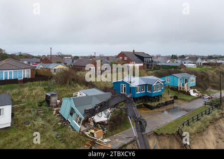 Abbrucharbeiter reißen das erste von fünf Häusern auf den Klippen des Dorfes Hemsby ab, das von der Küstenerosion betroffen ist. Hohe Fluten und starke Winde führten letzten Monat zum Zusammenbruch einer privaten Zufahrtsstraße in Hemsby in Norfolk. Bilddatum: Samstag, 9. Dezember 2023. Stockfoto