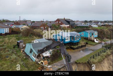 Abbrucharbeiter reißen das erste von fünf Häusern auf den Klippen des Dorfes Hemsby ab, das von der Küstenerosion betroffen ist. Hohe Fluten und starke Winde führten letzten Monat zum Zusammenbruch einer privaten Zufahrtsstraße in Hemsby in Norfolk. Bilddatum: Samstag, 9. Dezember 2023. Stockfoto