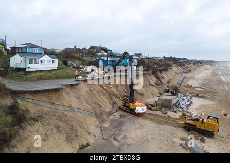 Abbrucharbeiter reißen das erste von fünf Häusern auf den Klippen des Dorfes Hemsby ab, das von der Küstenerosion betroffen ist. Hohe Fluten und starke Winde führten letzten Monat zum Zusammenbruch einer privaten Zufahrtsstraße in Hemsby in Norfolk. Bilddatum: Samstag, 9. Dezember 2023. Stockfoto