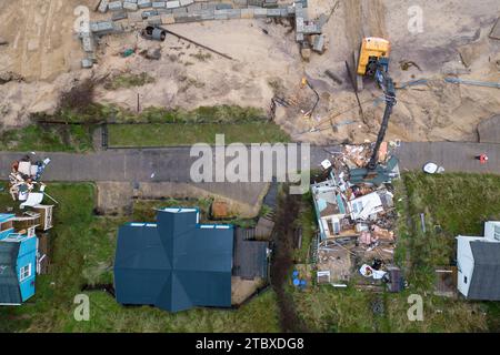 Abbrucharbeiter reißen das erste von fünf Häusern auf den Klippen des Dorfes Hemsby ab, das von der Küstenerosion betroffen ist. Hohe Fluten und starke Winde führten letzten Monat zum Zusammenbruch einer privaten Zufahrtsstraße in Hemsby in Norfolk. Bilddatum: Samstag, 9. Dezember 2023. Stockfoto