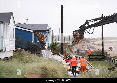 Abbrucharbeiter reißen das erste von fünf Häusern auf den Klippen des Dorfes Hemsby ab, das von der Küstenerosion betroffen ist. Hohe Fluten und starke Winde führten letzten Monat zum Zusammenbruch einer privaten Zufahrtsstraße in Hemsby in Norfolk. Bilddatum: Samstag, 9. Dezember 2023. Stockfoto