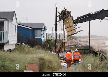 Abbrucharbeiter reißen das erste von fünf Häusern auf den Klippen des Dorfes Hemsby ab, das von der Küstenerosion betroffen ist. Hohe Fluten und starke Winde führten letzten Monat zum Zusammenbruch einer privaten Zufahrtsstraße in Hemsby in Norfolk. Bilddatum: Samstag, 9. Dezember 2023. Stockfoto