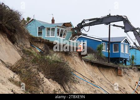 Abbrucharbeiter reißen das erste von fünf Häusern auf den Klippen des Dorfes Hemsby ab, das von der Küstenerosion betroffen ist. Hohe Fluten und starke Winde führten letzten Monat zum Zusammenbruch einer privaten Zufahrtsstraße in Hemsby in Norfolk. Bilddatum: Samstag, 9. Dezember 2023. Stockfoto