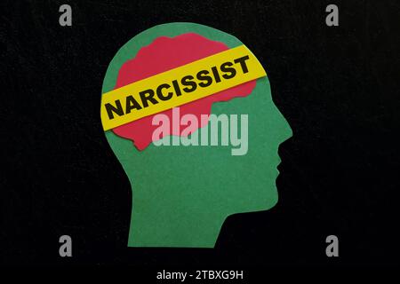 Menschliches Kopfprofil mit Wort Narzisst auf dunkelschwarzem Hintergrund. Narzisstisches Verhaltenskonzept. Stockfoto
