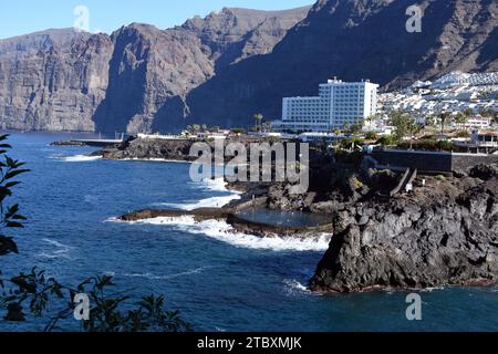 Los Gigantes dramatische Küste auf Teneriffa mit einem natürlichen Meerwasserpool und dem Dorf Los Gigantes und Hotel, das von vulkanischen Klippen umgeben ist. Stockfoto