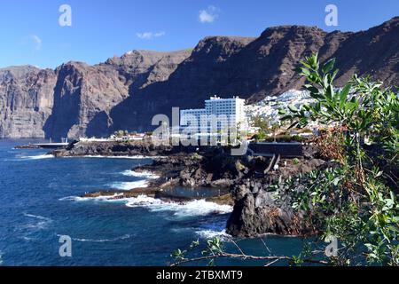 Los Gigantes dramatische Küste auf Teneriffa mit einem natürlichen Meerwasserpool und dem Dorf Los Gigantes und Hotel, das von vulkanischen Klippen umgeben ist. Stockfoto