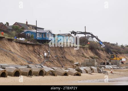 Abrissarbeiter reißen das zweite von fünf Häusern auf den Klippen des Dorfes Hemsby ab, das von der Küstenerosion betroffen ist. Hohe Fluten und starke Winde führten letzten Monat zum Zusammenbruch einer privaten Zufahrtsstraße in Hemsby in Norfolk. Bilddatum: Samstag, 9. Dezember 2023. Stockfoto