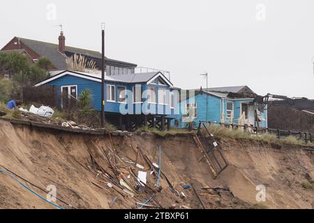 Abrissarbeiter reißen das zweite von fünf Häusern auf den Klippen des Dorfes Hemsby ab, das von der Küstenerosion betroffen ist. Hohe Fluten und starke Winde führten letzten Monat zum Zusammenbruch einer privaten Zufahrtsstraße in Hemsby in Norfolk. Bilddatum: Samstag, 9. Dezember 2023. Stockfoto