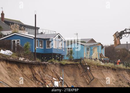 Abrissarbeiter reißen das zweite von fünf Häusern auf den Klippen des Dorfes Hemsby ab, das von der Küstenerosion betroffen ist. Hohe Fluten und starke Winde führten letzten Monat zum Zusammenbruch einer privaten Zufahrtsstraße in Hemsby in Norfolk. Bilddatum: Samstag, 9. Dezember 2023. Stockfoto