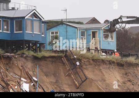 Abrissarbeiter reißen das zweite von fünf Häusern auf den Klippen des Dorfes Hemsby ab, das von der Küstenerosion betroffen ist. Hohe Fluten und starke Winde führten letzten Monat zum Zusammenbruch einer privaten Zufahrtsstraße in Hemsby in Norfolk. Bilddatum: Samstag, 9. Dezember 2023. Stockfoto