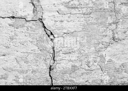 Großer vertikaler Riss mit langer Kurve an alter Putz- und lackierter Wand. Kopierbereich. Schwarzweißfoto. Selektiver Fokus. Stockfoto