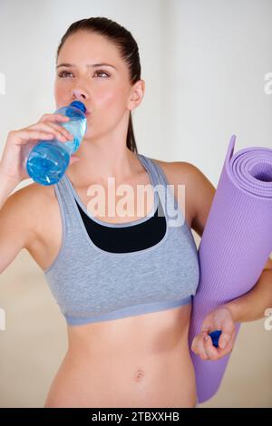 Gesundheit, Fitness und junge Frau Trinkwasser für Pilates Workout oder Training in Gym. Ernährung, Sport und durstige weibliche Athletin, die Feuchtigkeit genießt Stockfoto