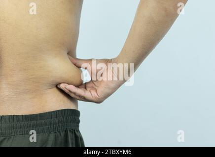 Mann, der Topfbauch oder Bauchfett berührt. Nahaufnahme von Körperteilen Stockfoto