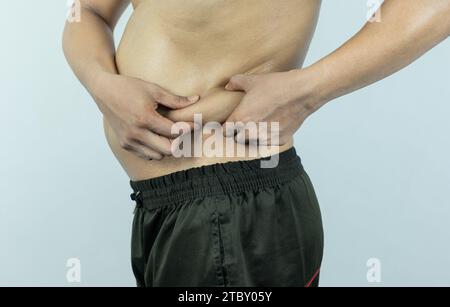 Mann, der Topfbauch oder Bauchfett berührt. Nahaufnahme von Körperteilen Stockfoto